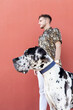 © Sergio Victor Vega/ADDICTIVE STOCK - Male owner standing with big Harlequin Great Dane dog during stroll in city and looking away
