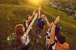 © Studio Romantic - High angle of team of happy tourists reaching out for high five while hiking on grassy hill