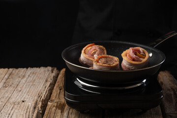 Chef prepares meat steaks in bacon, beef or pork. Chef on black background for restaurant menu text copy space