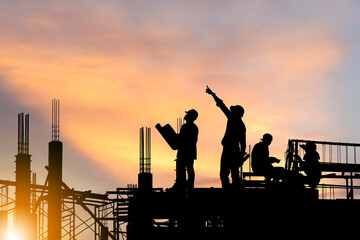 Silhouette of Engineer and worker on building site, construction site at sunset in evening time.