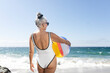 Mature woman holding a beach ball while in a swimsuit