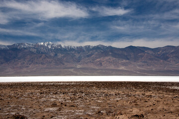 Wall Mural - Salt flats, cloudy sky and snowy mountains in the Death Valley National Park