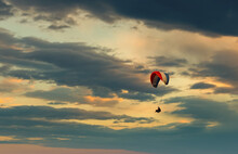 The Paraglider Flies In The Blue Sky Against The Backdrop Of Clouds.