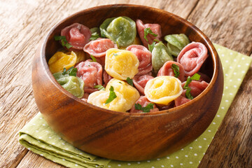 Red, green and yellow tortellini dumplings close-up in a bowl on the table. horizontal