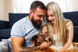 © fotofabrika - Young loving couple relaxing in living room with their dog pet