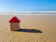© Valeriia - Colourful blue yellow red miniature wooden kids toy home model on sunny sand beach with blue sky, ocean background. Copy space of family lifestyle and business real estate property investment concept