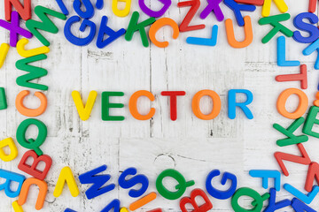 Fototapete - Brightly colored alphabet letters framing the word on a grey wood background viewed as a flat lay still life. Top view