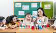 Diversity children doing a chemical experiment in laboratory at school. Portrait of happy kids at elementary school learning science chemistry with asian teacher. Fun study back to school concept.