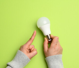 Poster - female hand holding white glass lamp, green energy