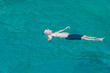 © Stockwars - Summer concept: A single Caucasian man with blue shorts is lying on the water. The guy is floating fearless over turquoise sea. Outdoors on a sunny day. Swimming activity on holiday.