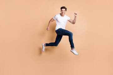 Poster - Full size profile photo of hooray brunet man jump run wear t-shirt jeans sneakers isolated on beige background