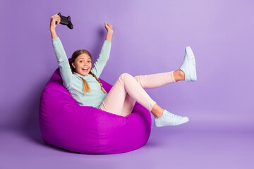 Sticker - Photo of small excited lady sit beanbag hold gamepad wear green sweater pants shoes isolated violet background