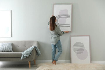 Wall Mural - Woman hanging picture on wall in room. Interior design