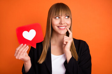 Poster - Portrait of beautiful trendy dreamy cheerful girl holding paper red card web like thinking isolated over bright orange color background