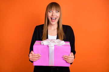 Canvas Print - Portrait of attractive amazed cheerful girl holding in hands giftbox having fun isolated over bright orange color background