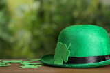 Fototapeta  - Leprechaun hat and clover leaves on wooden table against blurred background, space for text. St Patrick's Day celebration