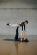 © BASILICOSTUDIO STOCK - Smiling sporty women training a difficult balance acrobat pose, strong bodies, concentration and determination. Fitness studio with concrete gray walls. Acro Yoga Pilates healthy lifestyle concept.