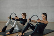 © BASILICOSTUDIO STOCK - Smiling brunette female coach showing a woman to practice Pilates stretching exercise with Magic circle Ring, workout during personal aerobic class in a fitness center gym, health club.