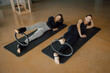 © BASILICOSTUDIO STOCK - Top angle of Two sporty attractive woman doing toning pilates exercise for legs and abs with Magic circle, Pilates Yoga Ring. Wearing sportswear, at Fitness studio, center, gymnasium.