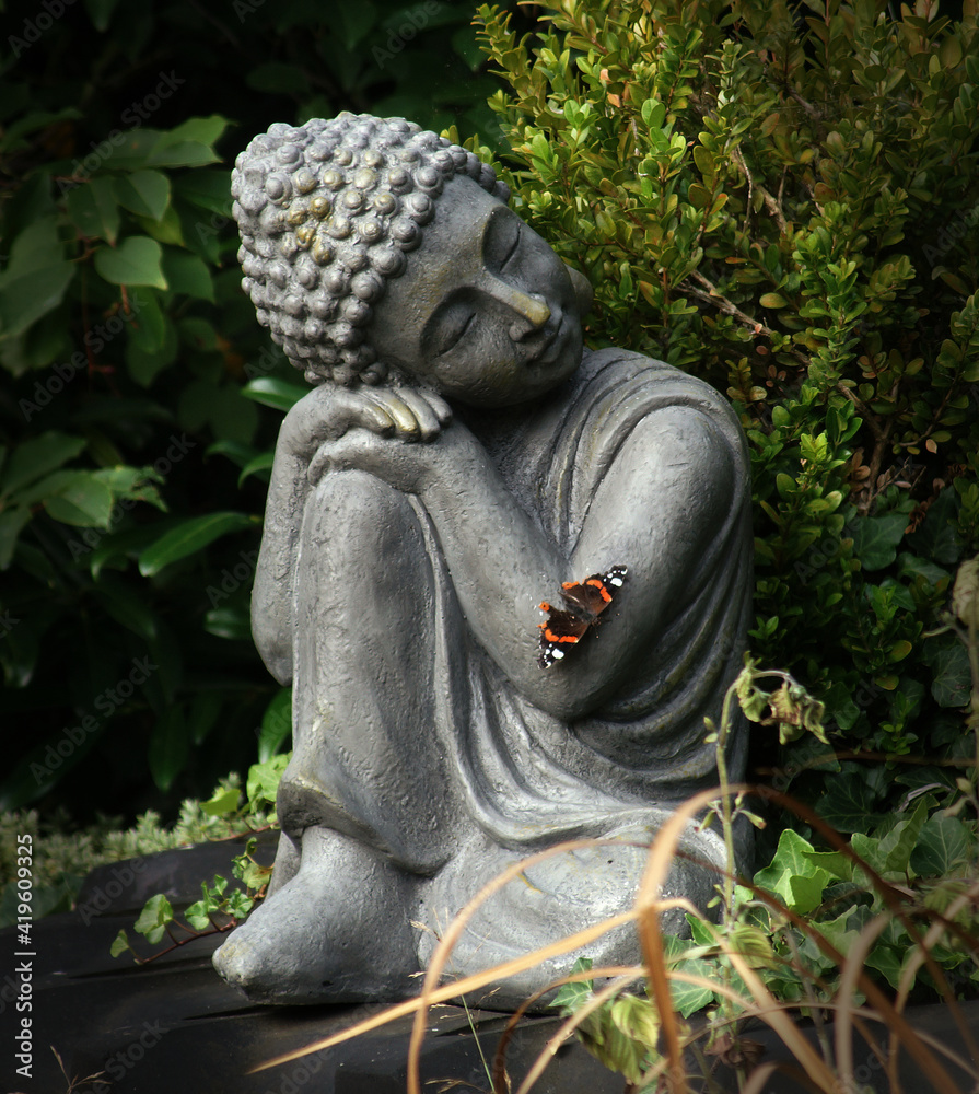 Buddha statue in the garden with a butterfly on his arm. This posture ...