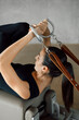 © BASILICOSTUDIO STOCK - Close up of brunette caucasian female hands with leather bands and strings of a Pilates Reformer machine. Rear view of a professional coach working out, exercising core and arms. Healthy lifestyle.