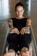 © BASILICOSTUDIO STOCK - Hands of a beautiful fit woman in sport clothing working out at gym. Front view of flexible female pulling strings of a pilates reformer machine in fitness center, rowing. Close up