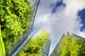 green city - double exposure of lush green forest and modern skyscrapers windows