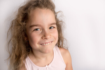 Attractive little girl stands on a white background with empty copy space, happy expression on her face with a beautiful smile, children crooked teeth, pediatric dentistry