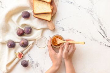 Woman with jar of sweet fig jam on grunge background