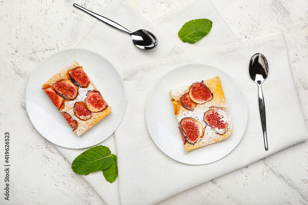 Plates with slices of delicious fig pie on light background