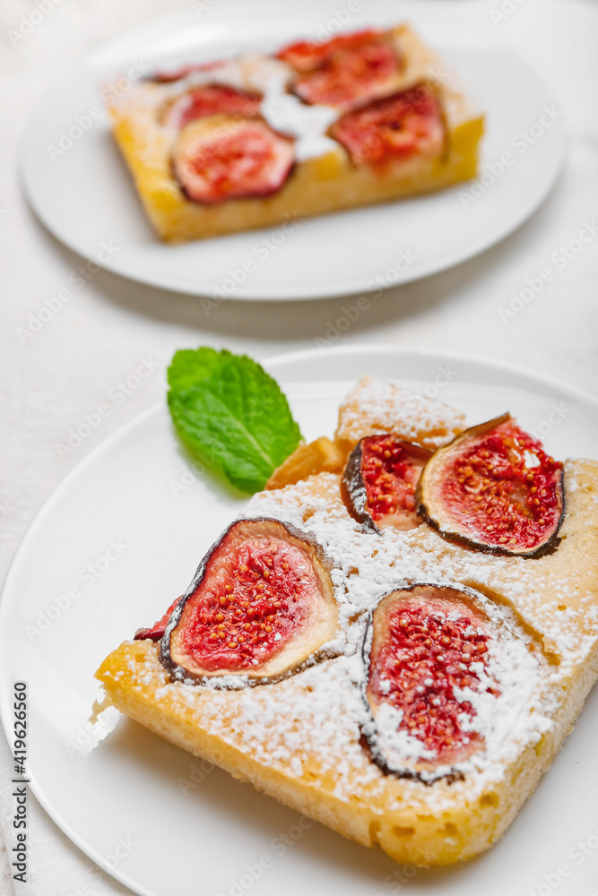 Plate with slice of delicious fig pie on light background