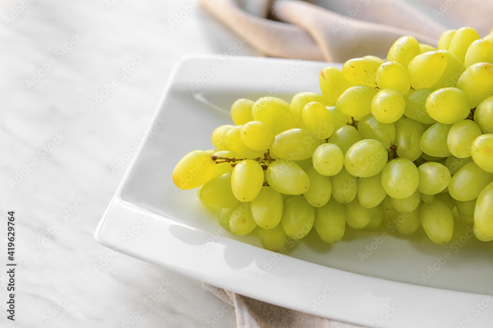 Plate with ripe green grapes on table