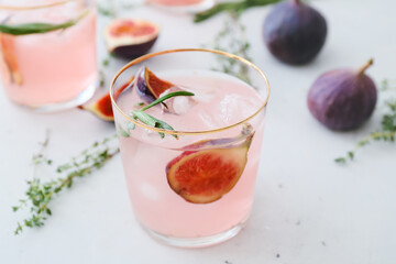 Glass of tasty fig lemonade on light background