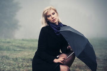 Wall Mural - Young fashion woman with umbrella walking in a fog outdoor