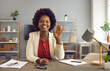 © Studio Romantic - Friendly african american business woman waving in front of webcam welcoming online conference attendees. Smiling female company employees enjoy virtual business communication and online negotiations.