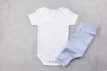 Wall Mural - White baby girl or boy bodysuit mockup on the gray concrete background with blue panties. Design onesie template, print presentation mock up. Top view. Flat Lay.