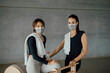 © BASILICOSTUDIO STOCK - Portrait of two happy sportive women with towels and face masks, relaxing after training at gym, having a break, looking at camera and smiling. Happy to return to the gym after Covid-19 pandemic.