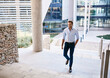 © marvent - Young businessman smiling while walking up stairs outside of an office