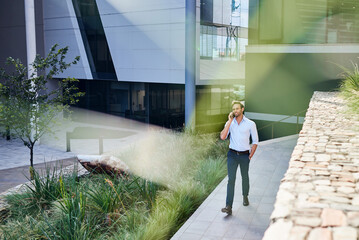 Businessman talking on his phone while walking outside of his office