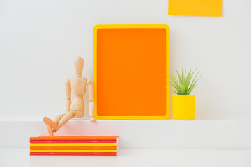 Yellow frame mock up, plant and notebooks on a desk in kids room.