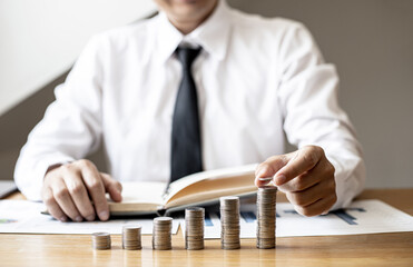 Businessmen are stacking coins on top of the highest row, stacking coins in a row from low to high is comparable to saving money for growth. Concept of saving money for investment.