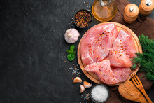 Raw Turkey Meat On A Round Board On A Black Background. Culinary Background With Space To Copy.