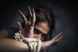Stop violence against women concept: Young woman tied up with rope in a dark room.  Helpless tortured or abused women. looking at with fear. Victim, slave, prisoner woman.