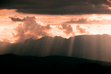 Stunning View Of A Sun Rays Breaking Through The Clouds And Alayered Mountain Silhouettes