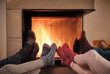 © Dirk Kittelberger/Westend61 - Family warming up feet in woolen socks by fireplace in living room