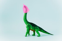 Diplodocus Dinosaur Toy With Pink Menstrual Cup On The Head On Mint Green Background