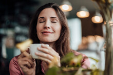 Smiling Businesswoman Smelling Coffee In Cafe