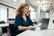 © Joseffson/Westend61 - Smiling businesswoman working on laptop at conference table in board room