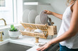 © Deidre - Woman washing dishes in kitchen using eco friendly brush and drying rack