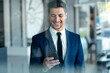 © JOSEP SURIA/Westend61 - Smiling entrepreneur wearing suit using mobile phone while standing in office